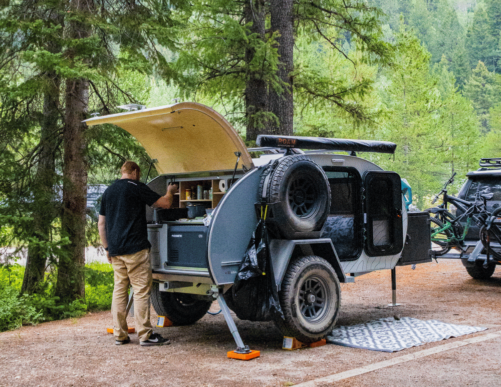 A man cooking in the galley of his Original TOPO teardrop trailer, by Escapod Trailer