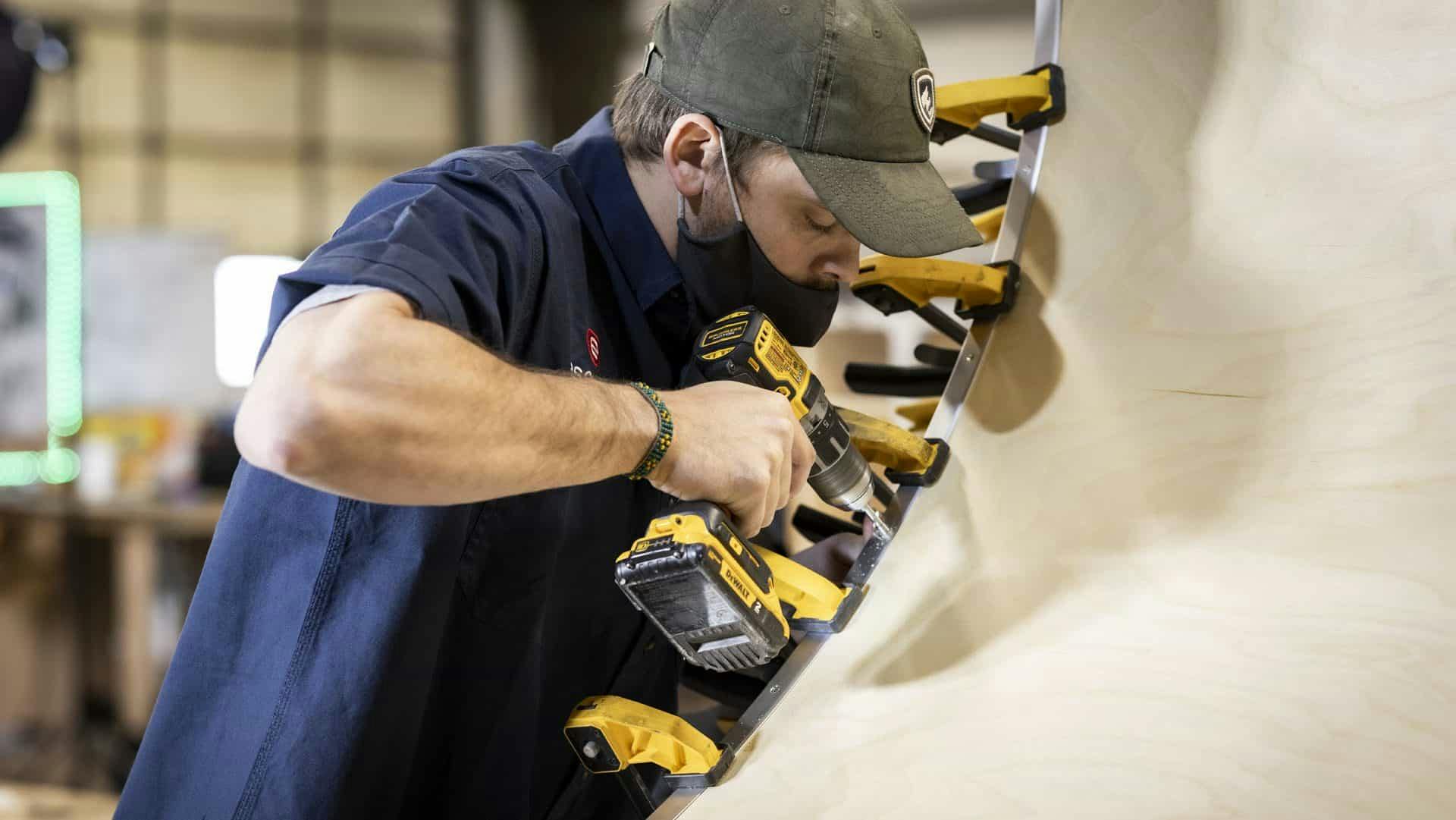 Craftsperson working to construct the hatch of a teardrop trailer.