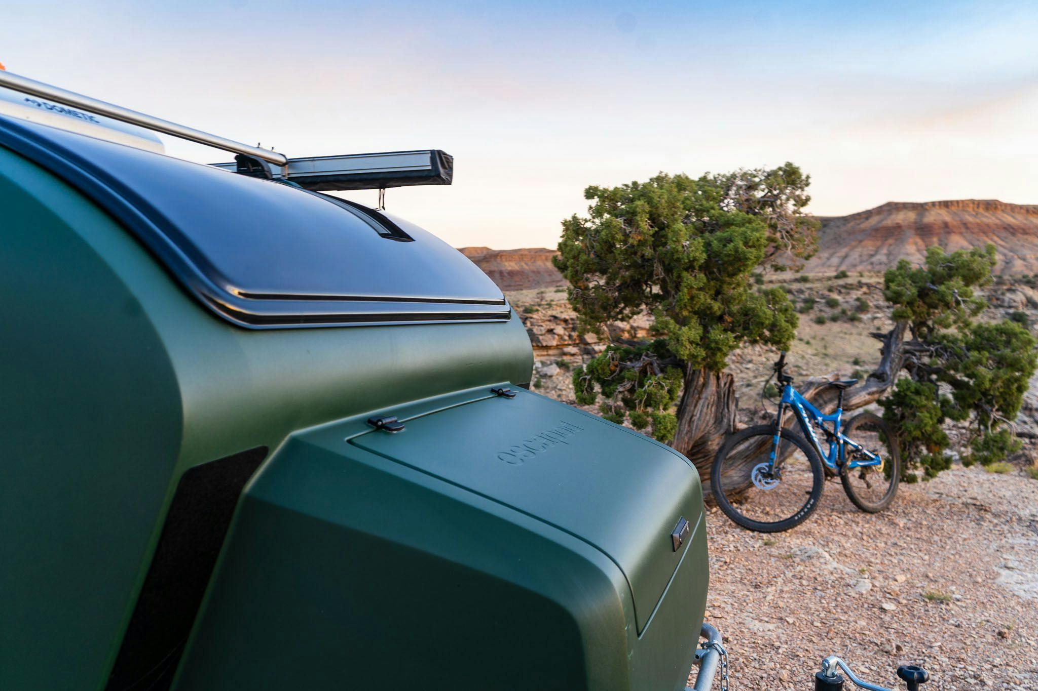 A green teardrop trailer with an integrated tongue box and stargazer window.