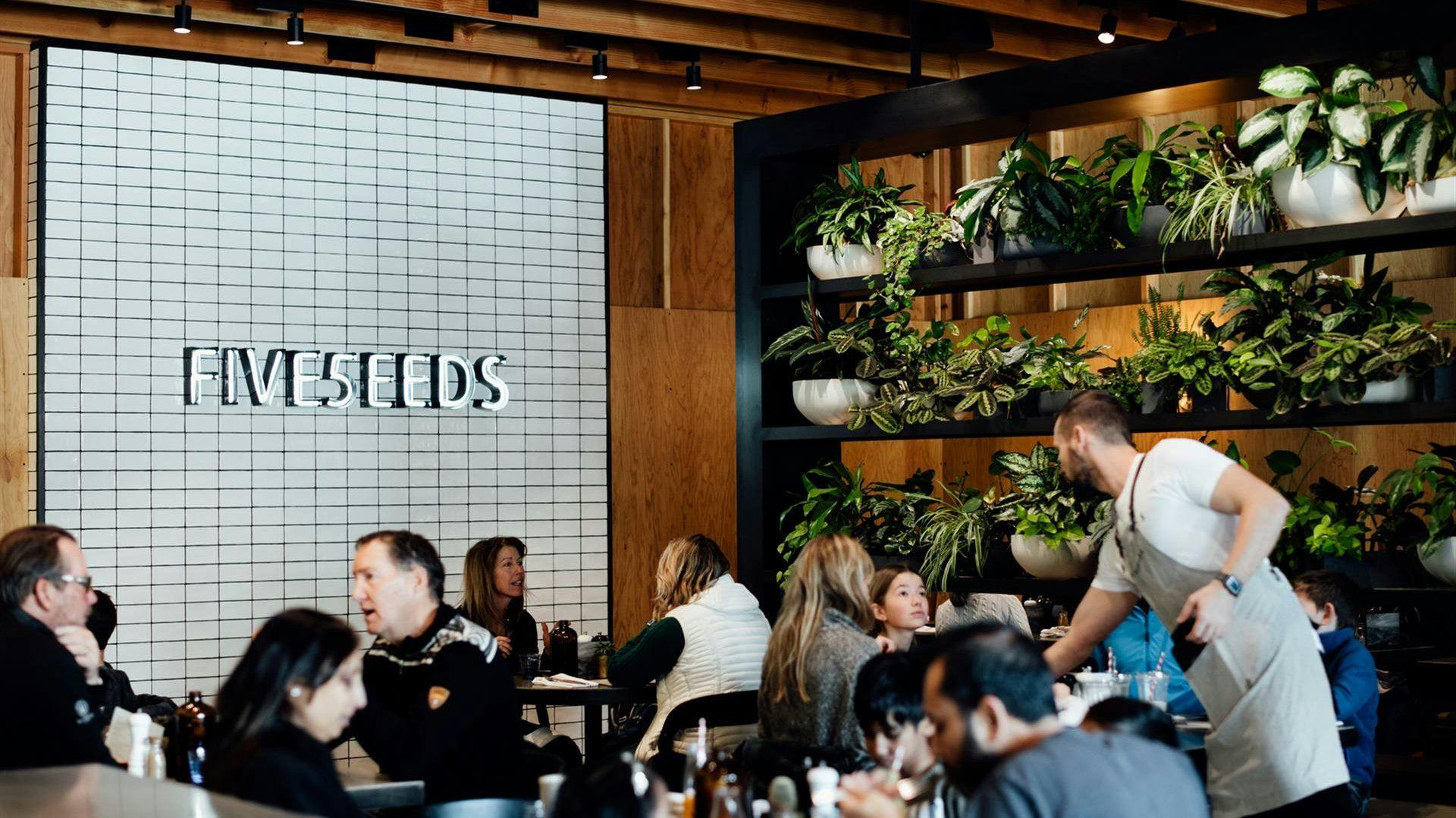 A restaurant with plants and people enjoying high quality food.