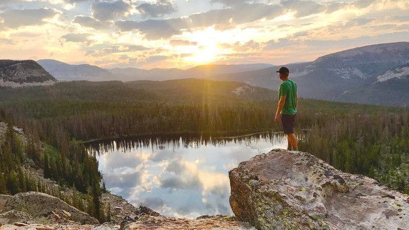 A man in a green tshirt standing on a rock ledge overlooking Pyramid Lake