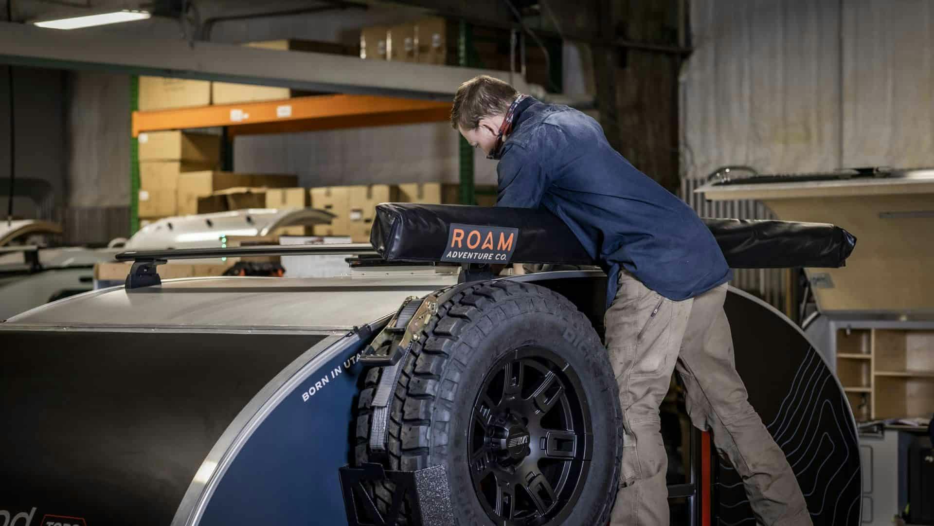 A craftsperson running final checks on the fan unit installed on a teardrop camper build.