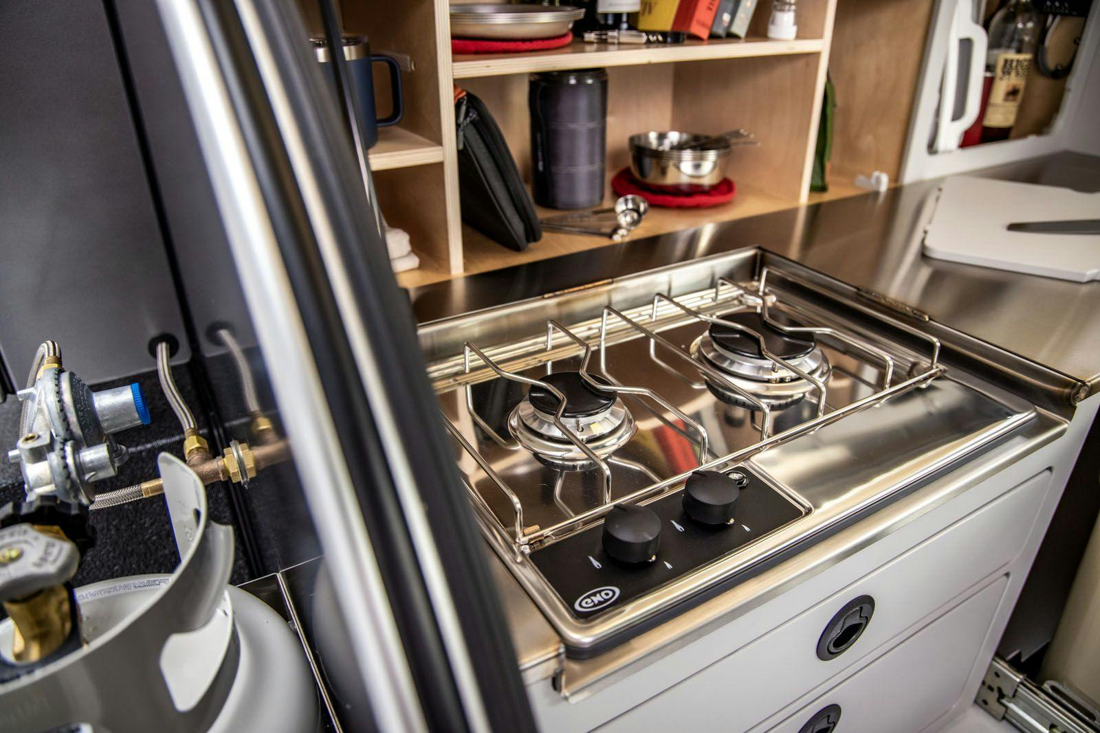 Close up of a ENO two-burner stove & propane tank on a teardrop camper.