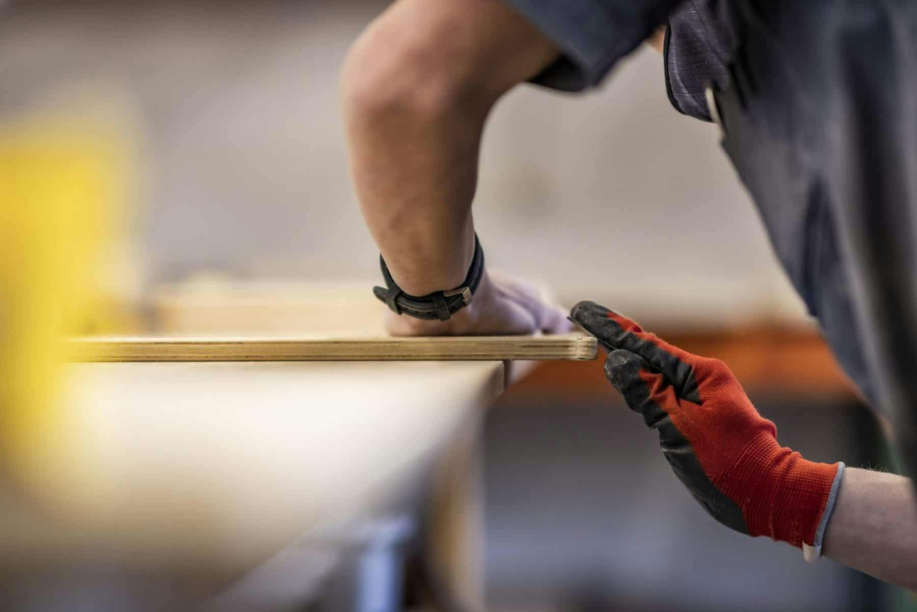 A craftsman working to refine the materials used in a teardrop camper build.