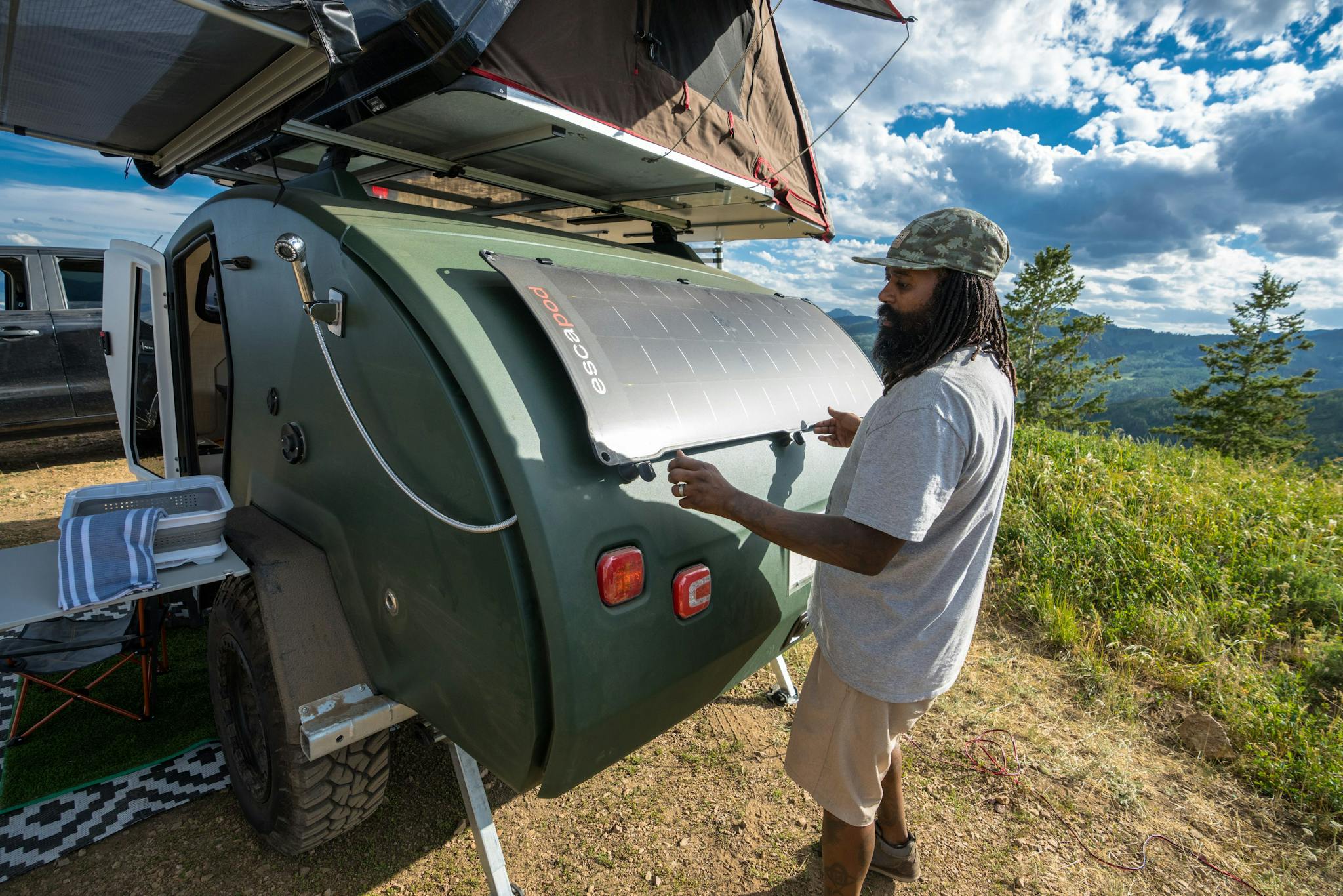 A man removing his solar panel off of his teardrop trailer to set it up in the sun.