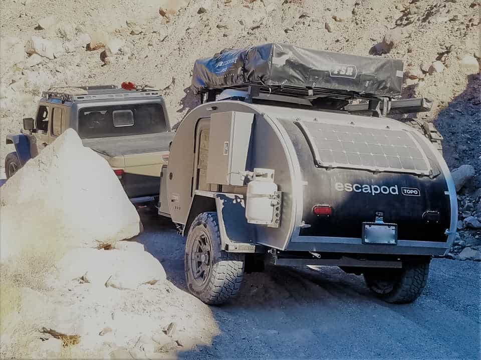 A grey and black offroad trailer, traveling over challenging terrain.