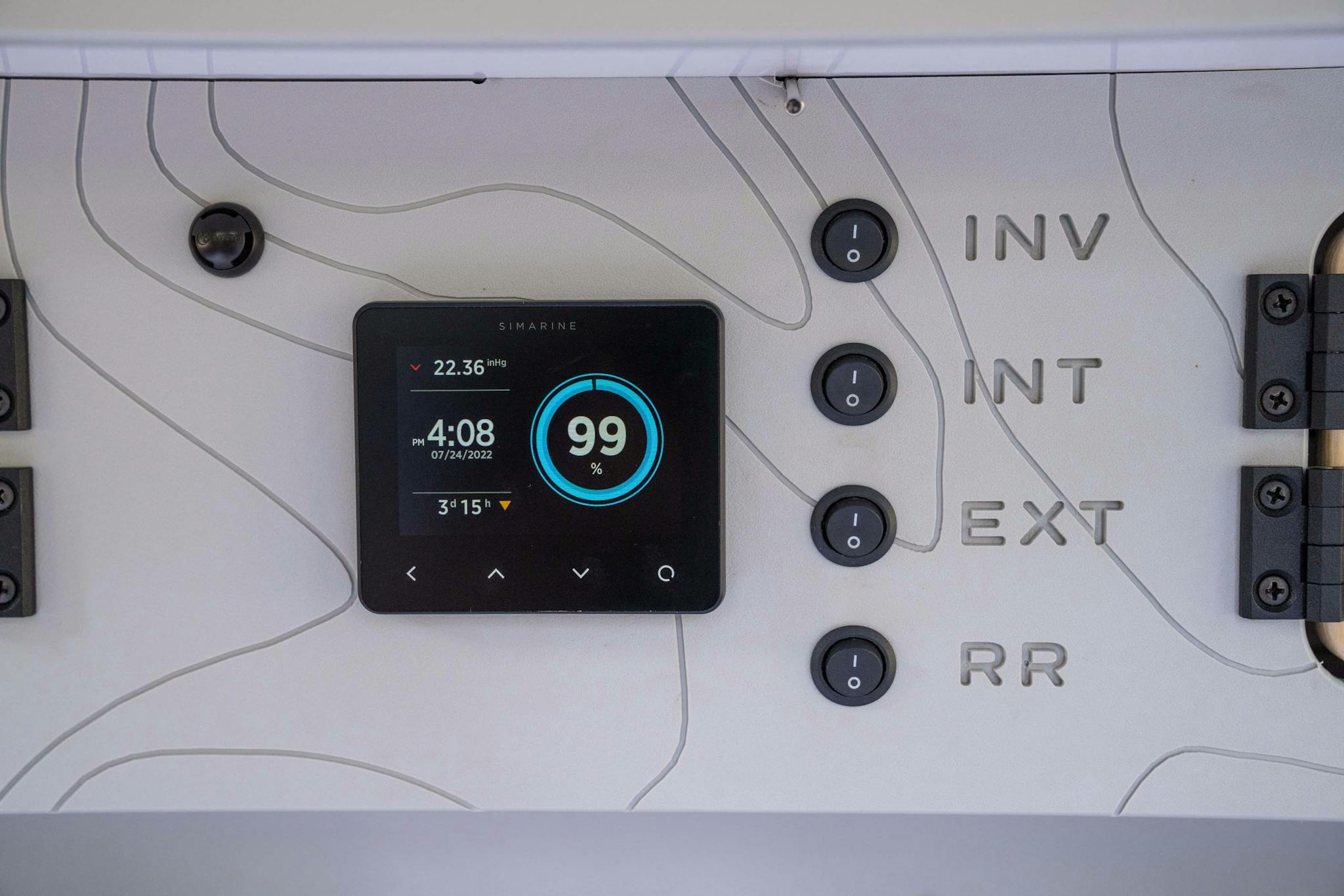 In the interior cabin of a teardrop camper a battery monitor is showing the amount of charge left of the battery.