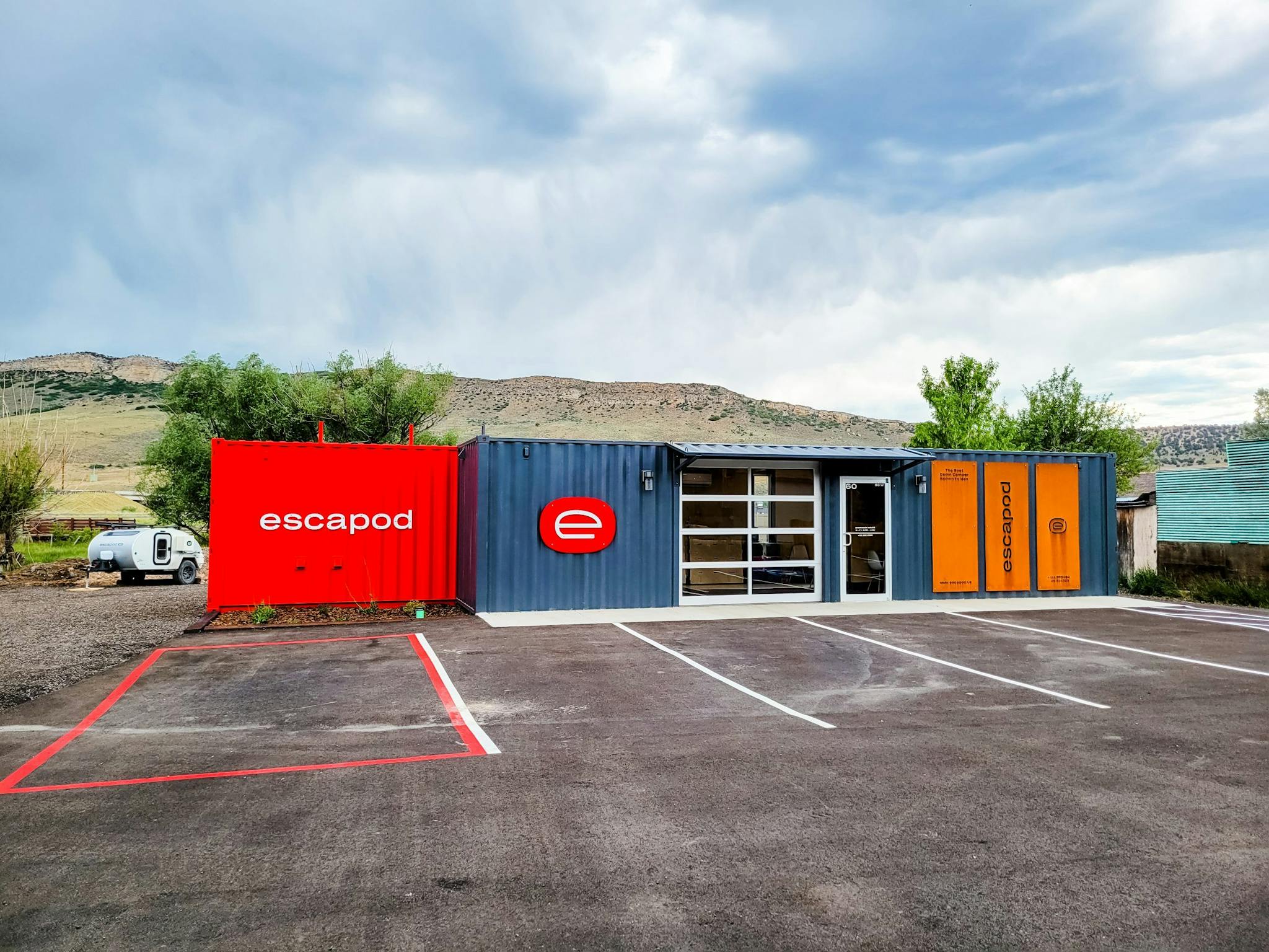 A red and greay facilty where people can people can pick up their tteardrop trailer.