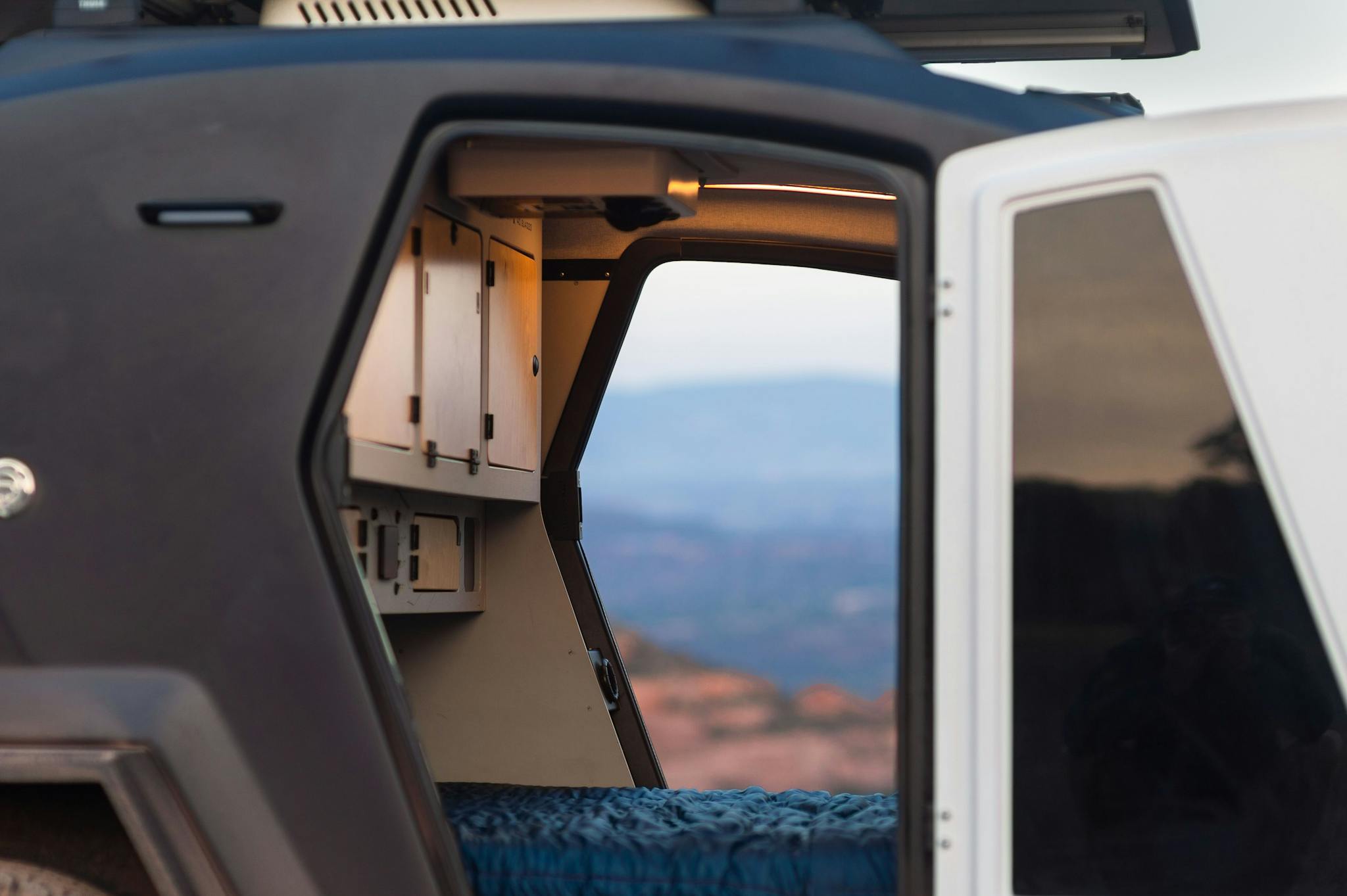 A teardrop trailer with both doors open to display a beautiful scene.