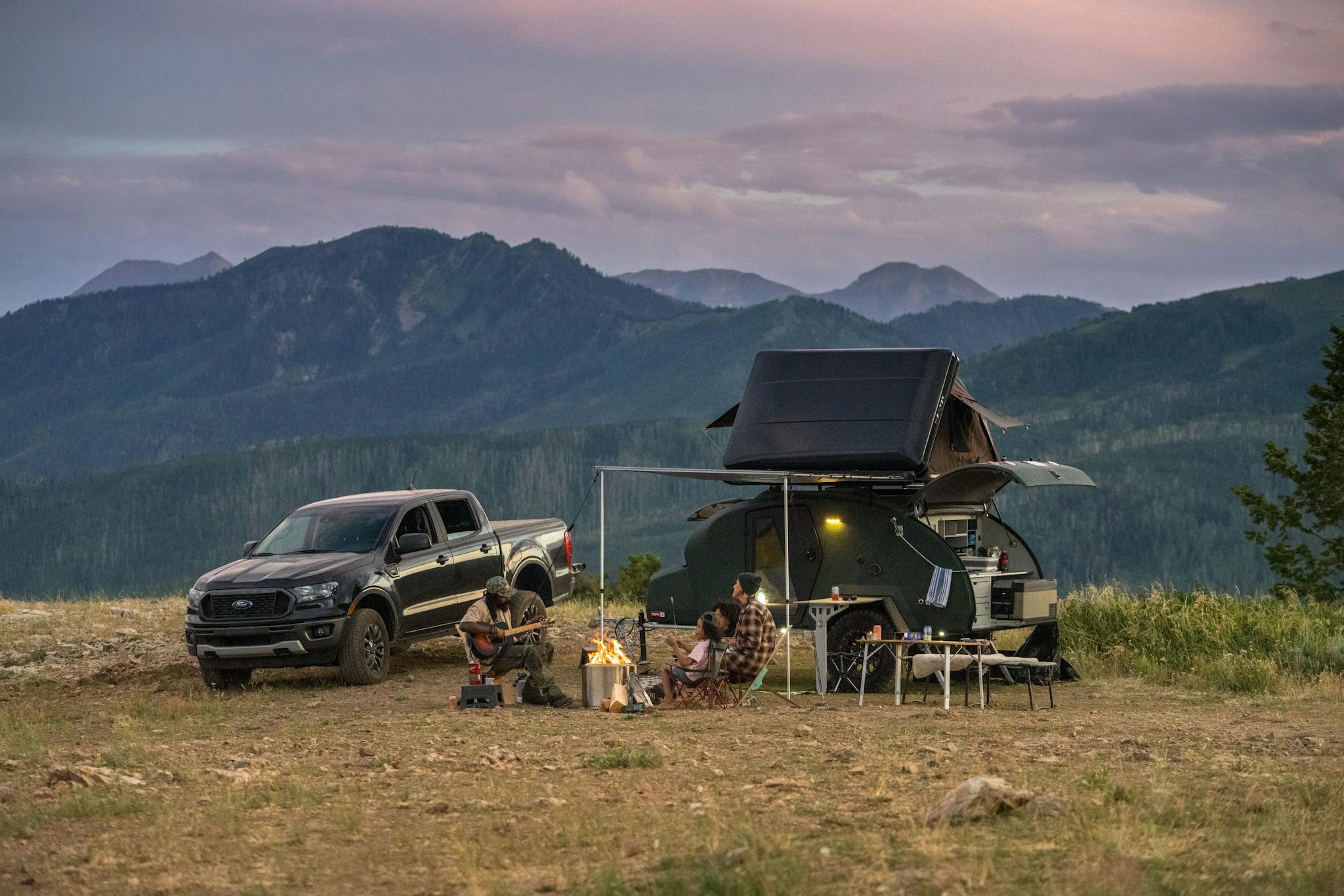 A family enjoying their time aroudn the fire in front of their adventure camper.