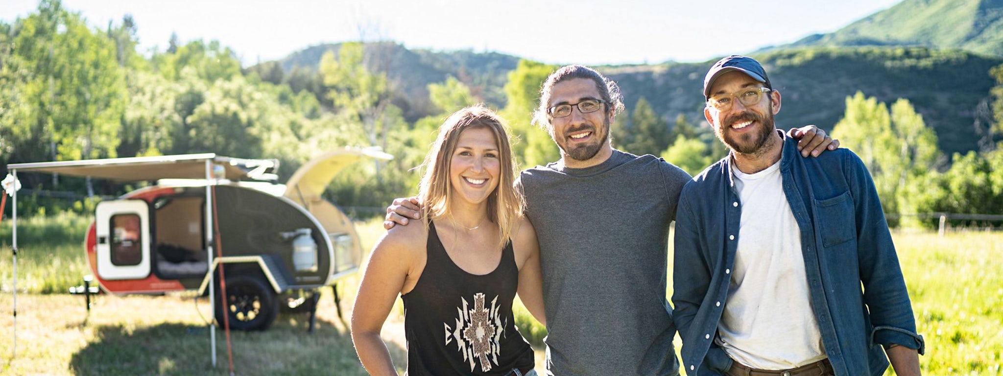 Image of three people in front of a teardrop camper.